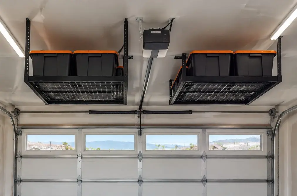 Illustration: two black overhead storage racks in a Murrieta, CA garage ceiling, bins on them, a sectional garage door with its track and the opener rail kept clear beside the racks